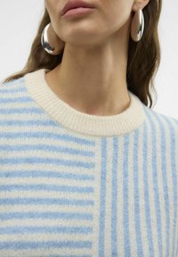 Maglione a righe con tonalità di blu chiaro e crema, in tessuto a maglia e con scollatura rotonda. Grandi orecchini metallici completano il look.