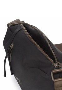 Zwarte nylon schoudertas met een bruine rits, voorzien van een ruime, gevoerde binnenkant en een riem voor gemakkelijk dragen.