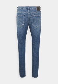 Slim-fit, mid-rise blå denimjeans med en urtvättad finish. Har två bakfickor och en läderpatch i midjan. Slät yta.