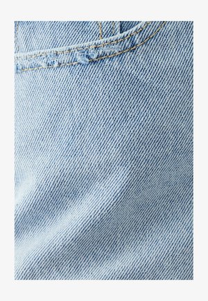 Heled sinine denimkangas, millel on veidi tekstureeritud pind, diagonaalis kootud mustritega ja näärinud servadega õmbluse lähedal.