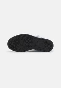 Semelle en caoutchouc noir de sneaker présentant des motifs texturés, une forme arrondie et un design circulaire central, offrant adhérence et stabilité.