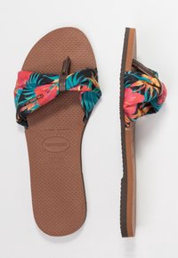 Infradito con suola in gomma marrone e cinturino in tessuto colorato con motivo floreale tropicale in rosa, arancione e teal.