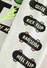 Tissu gris avec des skateboards noirs portant les mots : "OLLY", "KICK FLIP", "RAILSLIDE" et "HEEL FLIP" dans une police ludique. Accent vert néon.