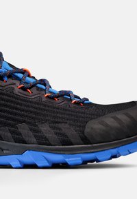 Svart löparsko med ett strukturerat tygövre, blå och orange snören, och en robust blå sula utformad för grepp.