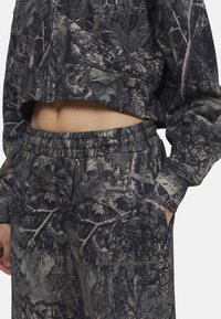 Korte sweatshirt en bijpassende broek in donkergrijs met een camouflagepatroon; gemaakt van gestructureerde stof; elastische tailleband en cuffs.