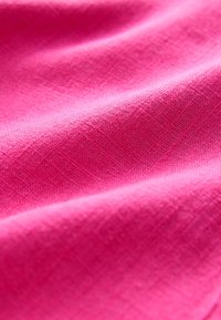 Tissu rose vif à la texture lisse, présentant un motif tissé subtil. Le matériau semble léger et légèrement brillant.