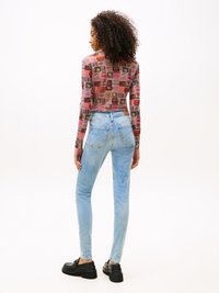 Camisa de manga longa com estampas coloridas e padrões, combinada com jeans skinny de ganga azul claro e sapatos de plataforma pretos.