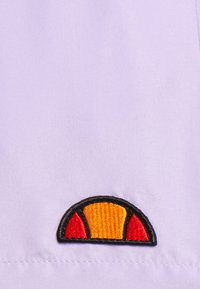 Alyvų spalvos audinys su juodai siuvinėtu logotipu, turinčiu pusapskričio dizainą, puošiamas oranžinėmis ir raudonomis akcentinėmis spalvomis. Lygus paviršius ir minimalistiška stilius.