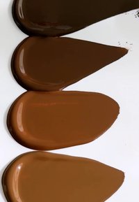 Vier Farbtöne brauner Farbe werden in Tropfenform auf einem weißen Hintergrund präsentiert, wobei sie von dunkel bis hell variieren und unterschiedliche Texturen und Glanzgrade zeigen.
