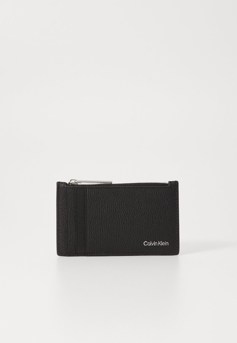 Portafoglio in pelle nera con superficie testurizzata, dotato di un compartimento con zip e slot per carte. Presenta un logo argentato sul davanti.
