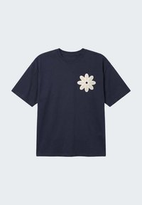 T-shirt manches courtes bleu marine avec un col rond et une marguerite beige brodée sur le côté gauche de la poitrine.
