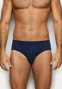 Bañadores azul marino hechos de una tela suave, con un estampado de pequeños chiles rojos. Cintura elástica con una textura suave.