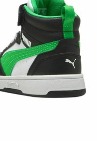 Sneakers alte con una parte superiore in pelle nera e dettagli verdi e bianchi. Materiali lavorati e un logo Puma ben visibile sul tallone.