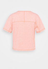 Kortærmet sportsbluse i lys koralfarve. Blødt, tekstureret stof med kontrastsyninger og rund halsudskæring.