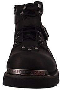 Bota de cuero negra con herrajes metálicos, puntera redonda, sistema de cordones robusto y una placa de marca plateada en el costado. Acabado texturizado y diseño resistente.