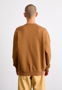 Sudadera de algodón marrón con mangas largas y un dobladillo acanalado, mostrada desde la parte de atrás. Textura suave y diseño de cuello redondo simple.