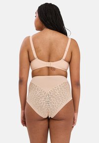 Reggiseno beige e slip a vita alta, con dettagli in pizzo floreale sul retro e texture liscia. Spalline regolabili e chiusura a gancio visibili.