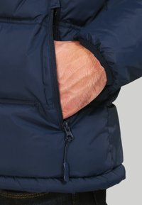 Námořnická prošívaná bunda s kapsou na zip a elastickými manžetami. Materiál působí hladce a je zateplený, určený pro teplo a pohodlí.