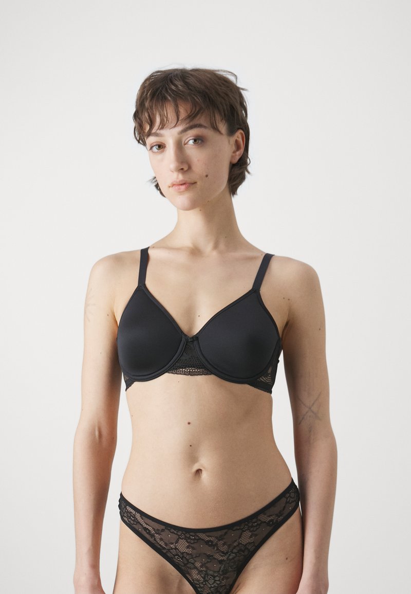 Svart bh med underwire, glatte kopper, blondekant og justerbare stropper. Kombinert med en matchende svart blonde stringtruse.