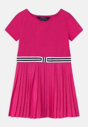 Robe rose vif à manches courtes avec jupe plissée et ceinture blanche et marine rayée avec un nœud à la taille.