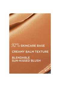 Blush à la texture baume crémeuse avec une base de soins de 92 %, décrit comme modulable et effet coup de soleil sur un fond lisse aux tons chauds.