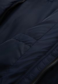 Granatowa kurtka puchowa z tkaniny, z pikowaną fakturą i gładkim wykończeniem. Zamek błyskawiczny wzdłuż krawędzi oraz subtelne detale stębnowania widoczne.