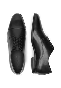 Melnas ādas vakara apavus ar gludu apdari, norādītām pirkstiem, dekoratīvām šuvēm un zemu papēdi. Iespēju klasiskā saitēšana.