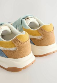 Suede and mesh sneakers featuring a beige, yellow, and blue color scheme, with a textured finish and a thick white midsole.