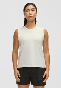 Biała bezrękawnik z miękkiego materiału o okrągłym dekolcie. Połączony z czarnymi, luźnymi szortami z bocznymi kieszeniami.