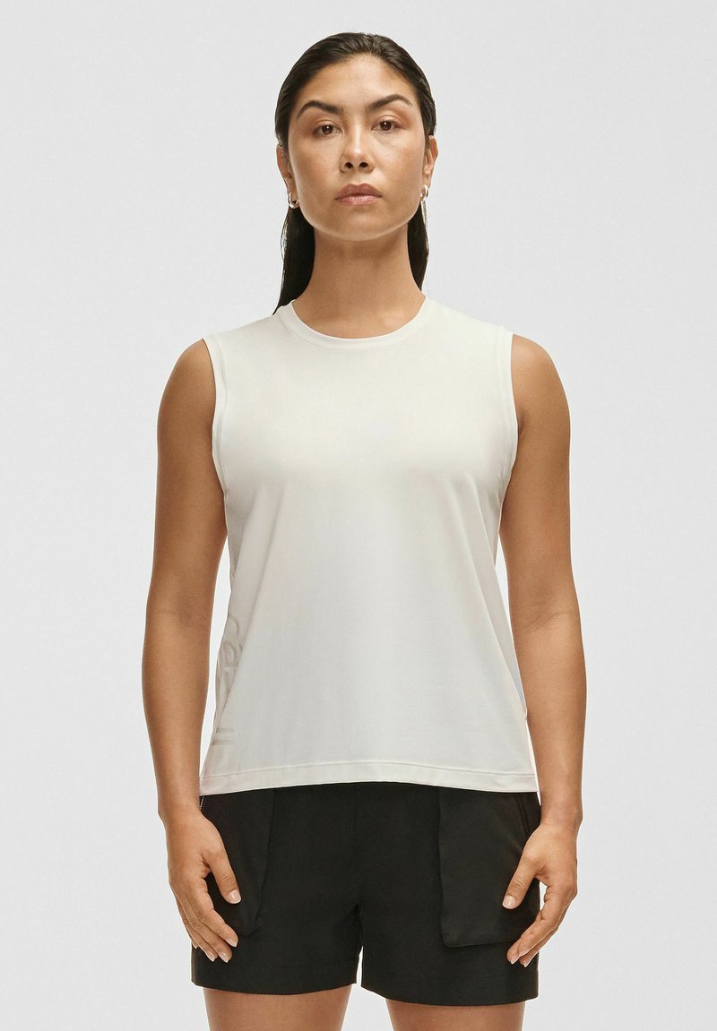 Biała bezrękawnik z miękkiego materiału o okrągłym dekolcie. Połączony z czarnymi, luźnymi szortami z bocznymi kieszeniami.