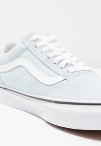 Lyseblå lærrem med hvite snøringer, med hvit sidestripe, teksturerte semskede detaljer og flat hvit gummisåle.