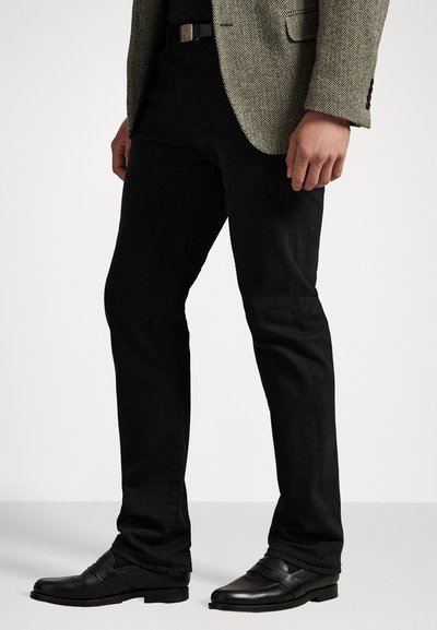 Calças justas pretas, feitas de uma mistura de algodão, com uma textura suave e um leve elástico, combinadas com um blazer em padrão de espinha de peixe.