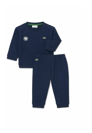 Completo composto da top blu navy a maniche lunghe e pantaloni con vita elastica con loghi di coccodrillo verdi e un emblema Roland Garros sul petto in alto a sinistra.