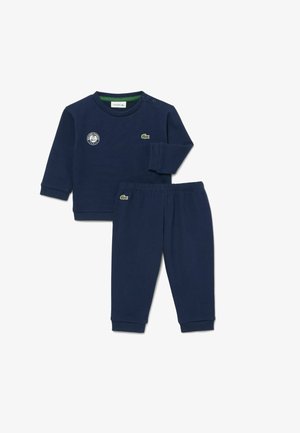 Marineblaues langärmliges Oberteil und eine Hose mit elastischem Bund mit grünen Krokodil-Logos und einem Roland-Garros-Emblem auf der oberen linken Brust.