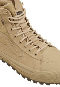 Brązowe buty VANS Off The Wall z mieszanką zamszu i tekstylnego wierzchu, okrągłym noskiem, wzmocnioną gumową osłoną na palce oraz solidną, bieżnikowaną podeszwą.