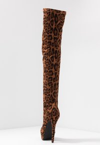 Botín de tacón stiletto hasta la rodilla en ante marrón con estampado de leopardo, que presenta una punta afilada y un tacón alto delgado con un acabado texturizado.