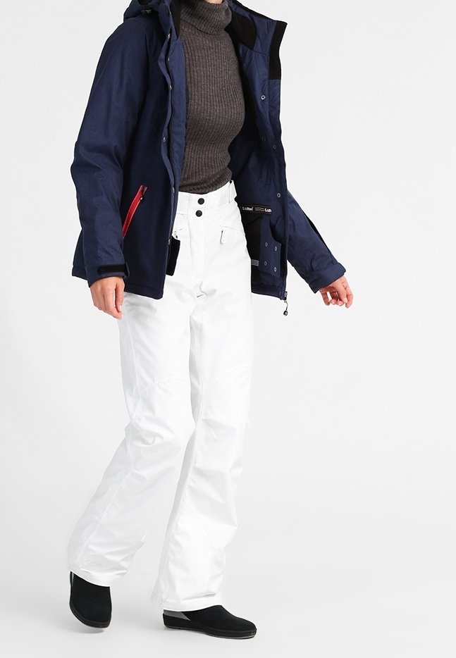 Marineblaue wasserdichte Jacke mit Kapuze und roten Reißverschlussdetails, kombiniert mit weißen isolierten Hosen. Das Outfit besteht aus einem strukturierten grauen Pullover und schwarzen Stiefeln.