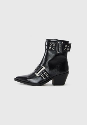 Svart lær ankle boot med spiss tå, sølvfargede spenne-detaljer og to stropper med hull. Lav blokkhel for ekstra stabilitet.