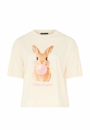 Camisa de manga corta color blanco roto con un conejo marrón soplando una burbuja de chicle rosa y texto rosa "Dando un salto a la primavera" debajo.