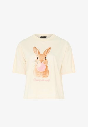 Off-white kort mouw shirt met een bruine konijn die op een roze kauwgombel blaast en roze tekst "Popping into spring" eronder.