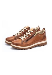 Baskets en cuir marron avec des lacets beige et une fermeture éclair sur le côté, présentant une semelle en caoutchouc texturée et une semelle intermédiaire de couleur claire contrastante.