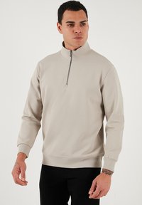 Svetlo béžový pulóver na zips s výstrihom, s rebrovanými manžetami a lemom, s textúrovaným povrchom a strieborným zipsom na golieri.
