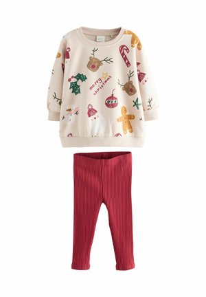 Helles rosa Sweatshirt mit festlichen Mustern, darunter Lebkuchen und Schneemänner, kombiniert mit gerippten roten Leggings. Weiche, dehnbare Materialien.
