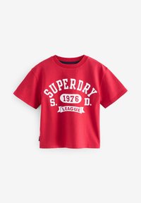 Camiseta roja de manga corta hecha de algodón con cuello redondo. Presenta un texto gráfico blanco que dice "SUPERDRY S.D. 1976 LEAGUE."