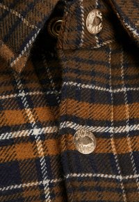 Brun och marinrutigt flanellskjorta med metallknapp med "Jack & Jones" ingraverat. Synlig textur och vävmönster.