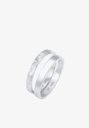 Strieborné prstene, jeden hladký a leštený, druhý textúrovaný s matným povrchom. Oba označené "925", čo indikuje striebornú zliatinu.