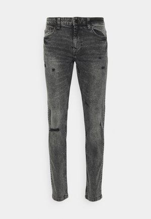 Grijze denim jeans met een slanke pasvorm. Heeft versleten details, vijf zakken en een knoopsluiting. Textuurstof met subtiele vervaging.