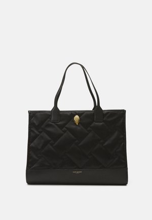 Sac fourre-tout noir matelassé en nylon avec une base en cuir lisse. Dispose de deux poignées et d'un emblème doré à l'avant.