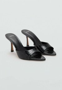 Mules negros de tacón con un patrón texturizado similar al de un cocodrilo, con punta abierta y un diseño elegante. Presentan un tacón delgado y una plantilla con marca.