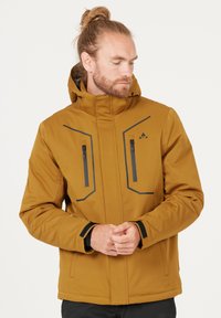 Brun kviltad jacka med huva, med svarta dragkedjefickor och geometriska accentlinjer, tillverkad av ett slätt, hållbart tyg.